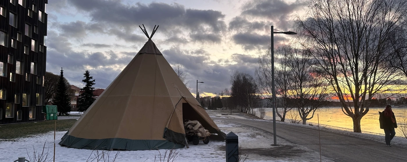 A teepee sitting on top of a snow covered ground.