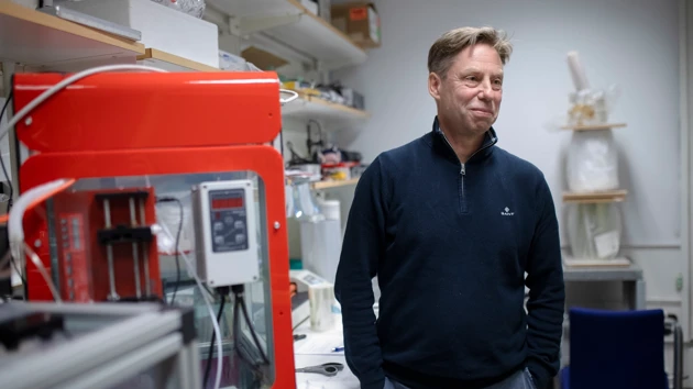 A man in a lab with equipment around him.