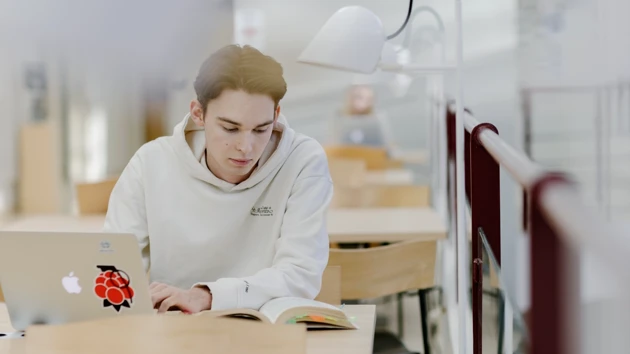 Studenten Hugo pluggar med dator och anteckningsblock.