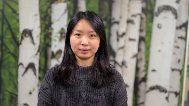 A woman standing in front of a painting of trees